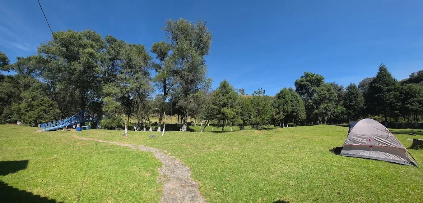 Campo de camping con el puente sobre el río al fondo